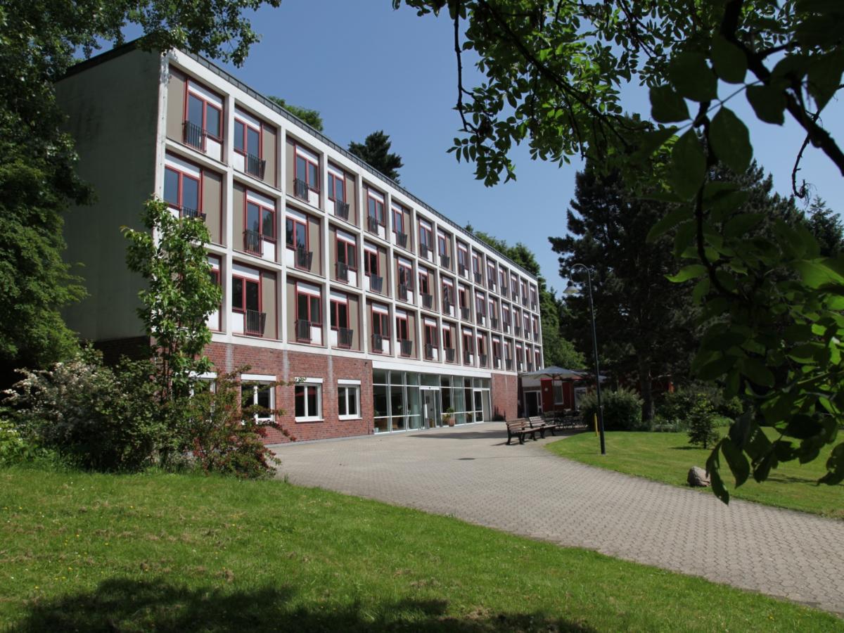 Ansicht von derlinken Seite aus auf das Haus Marienhof. Äste fallen am oberen rechten Bildschirmrand in das Bild herein.